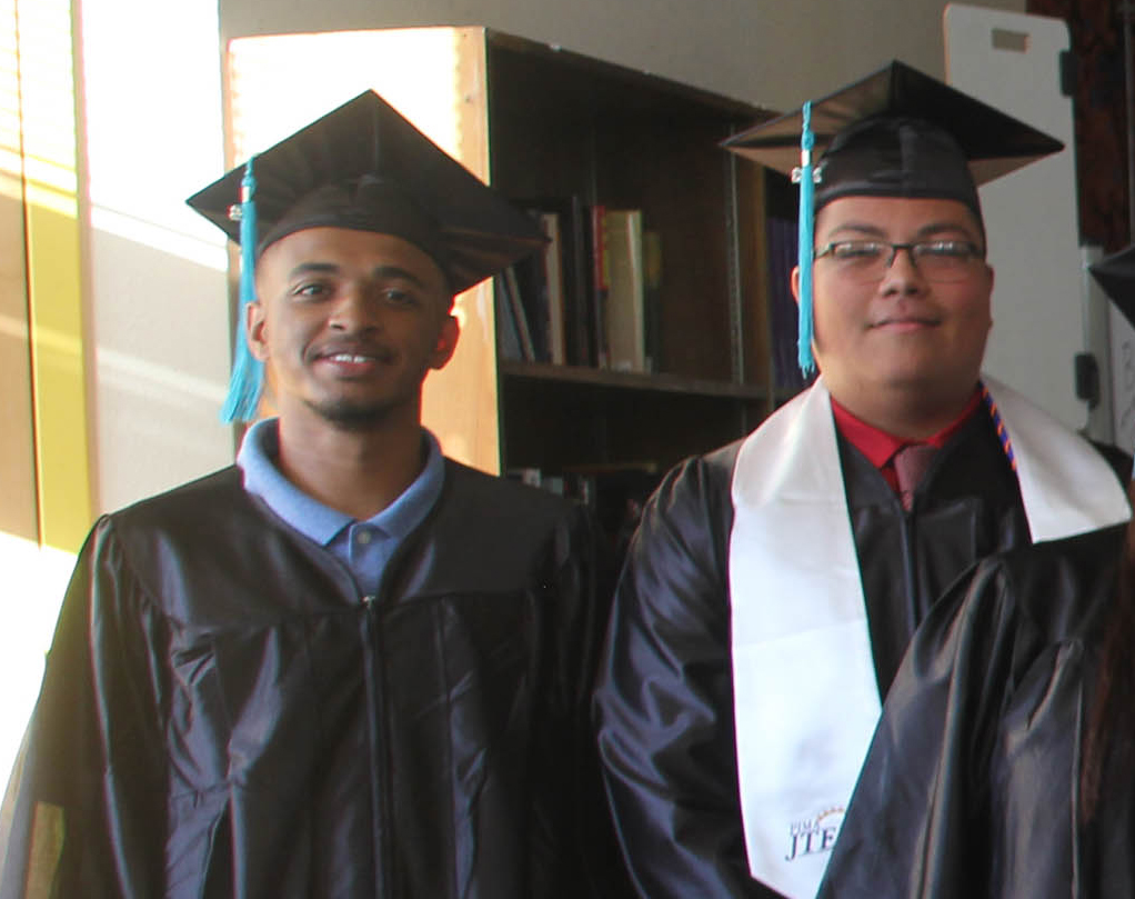 Three graduating students smiling at the camera.