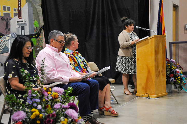 A woman addresses the graduates and audience