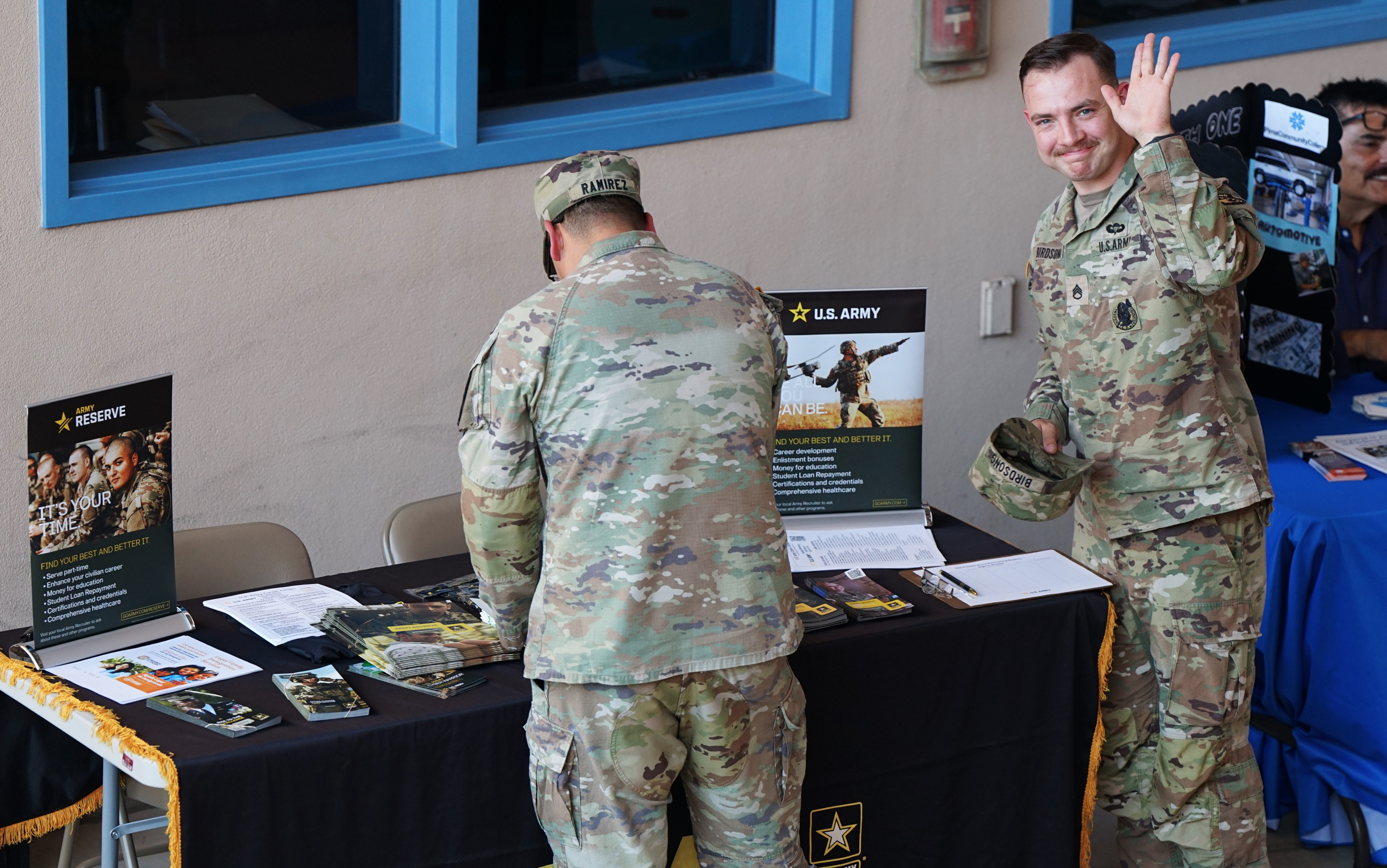 An Army officer in fatigues gives a wave from the U.S. Army table at the fair