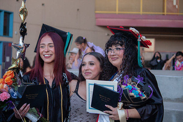 Two teen girls pose with their friend during graduation