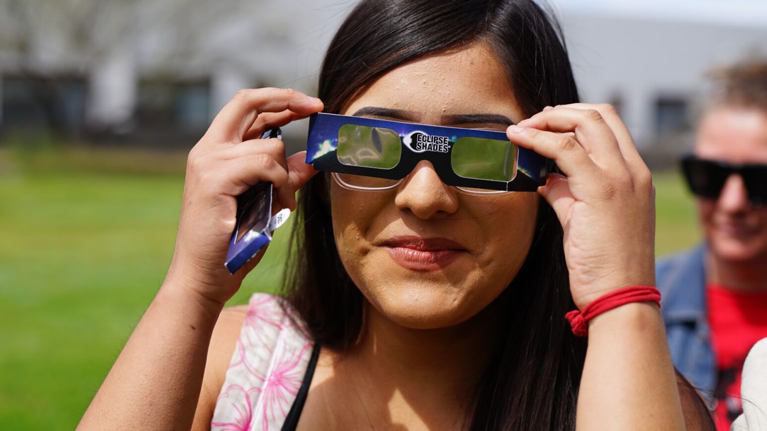 A teen girl smiles while looking at the eclipse through her special glasses