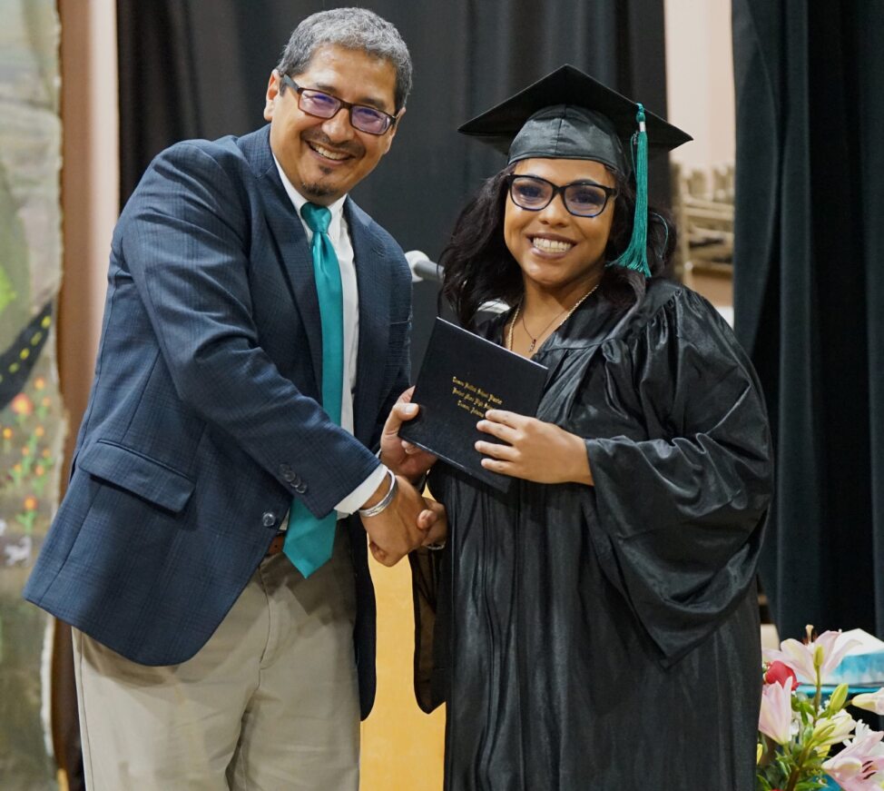 A Project MORE grad smiles as she shakes her principal's hand