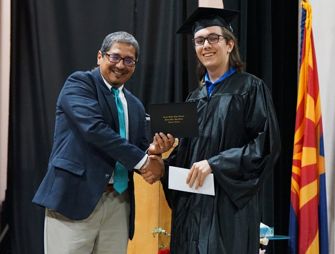 A Project MORE grad smiles as he gets his diploma from the principal